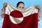 Young girl holding in both hands the national flag of greenland on beautiful shiny silk against a blue sky, state concept, travel