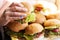 Young girl holding in female hands fast food burger, american unhealthy calories meal on background