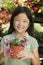 Young girl holding potted flowers in plant nursery portrait