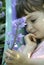 A young girl holding a stem of bluebell flowers