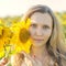 Young girl holding sunflowers outdoor shot. Portrait of beautiful blonde girl with bright yellow sunflower in hands on sunflowers