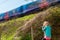 Young girl holding on to a wooden post as a high speed train passes by