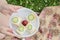 A young girl holds a plate with four small sandwiches with melted cheese ,cucumber slices and one plum in the center