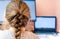 Young girl at home sitting at blank screen of desktop computer, rear view. Back to school, homeschooling, distance