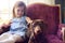 Young Girl At Home Stroking Pet Dachshund Dog Sitting On Chair