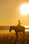 Young girl horseback riding on the beach at sunset