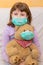 Young girl huge a teddy bear with medical mask