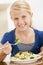 Young girl indoors eating pasta with brocolli