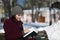 Young girl intently turns pages of a book, sitting on a bench in