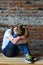 Young girl in jeans and white T-shirt is sitting on the floor and crying. Concept of a non happy and sad teenager