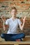 Young girl in jeans and white T-shirt is sitting on the floor and meditates. Concept portrait of a pleasant friendly happy