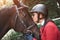 A young girl jockey talking and kissing her horse. She loves the animals and joyfully spends her time in their environment