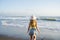 Young girl jumping and running waves at beach on sunset time.