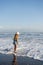 Young girl jumping and running waves at beach on sunset time.