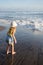 Young girl jumping and running waves at beach on sunset time.