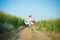 Young girl jumping with suitcase on road in corn