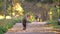 Young girl in jumpsuit with earphones running in autumnal park, stops to tie her snickers and continues jogging.