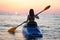 Young girl on the kayak greets the dawn of the sun