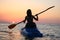 Young girl on the kayak greets the dawn of the sun