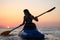 Young girl on the kayak greets the dawn of the sun