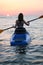 Young girl on the kayak greets the dawn of the sun