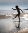 Young girl kicks the water at the beach holiday