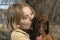 A young girl kisses and hugs a dachshund puppy.