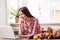 Young girl at kitchen healthy lifestyle leaning on table browsing internet on laptop cheerful near bag with products