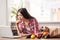 Young girl at kitchen healthy lifestyle leaning on table reading news on laptop concerned near bag with products