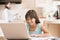 Young girl in kitchen with laptop and paperwork