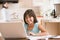 Young girl in kitchen with laptop and paperwork