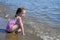 Young Girl kneels in the surf on a beach.