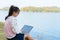 Young girl with laptop sitting on the riverbank