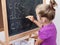 Young girl learning to write letters on blackboard
