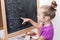 Young girl learning to write letters on blackboard