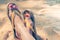 Young girl legs and flip-flop on the sand beach