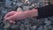 A young girl lies on the seashore unconscious, without movement. Close-up of a girl`s hand lying on a rocky shore.