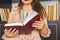 Young girl in light-colored dress choosing books in the vintage university library, reading book and relaxing.