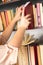 Young girl in light-colored dress choosing books in the vintage university library, reading book and relaxing.