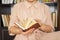 Young girl in light-colored dress choosing books in the vintage university library, reading book and relaxing.