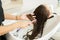 Young girl with long brown hair, combing and unraveling her head in the hairdresser`s. Social distancing. Use of the face mask.