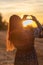 Young girl with long hair holding hands in the form of a heart against the backdrop of sunset, Poland