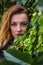 Young girl with long hair standing near the wall with wild grapes leaves sunny autumn day