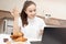 A young girl looks at a laptop, communicates on social networks at breakfast