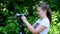 Young girl looks into video camera on background of green park slow motion.