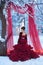 A young girl in a lush Marsala dress on the background of a dark red wedding decor