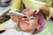 A young girl is lying on couch with a pink hat on her hair while performing an ultrasonic face cleaning with a special device for