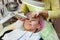 A young girl is lying on couch with a pink hat on her hair while performing an ultrasonic face cleaning with a special device for