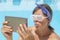 Young girl making selfie by the pool with a tablet wearing rave