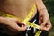 young girl measuring her waistline with a yellow flexible tape measure